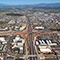 Aerial view of a sprawling suburban city with a complex freeway interchange in the center with blue mountains in the distance under a clear blue sky