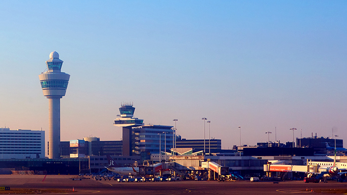 Pista de aeropuerto con una gran torre de control y varios vehículos en la pista 