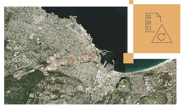 緑の陸地とグレーの建物、およびチェック マークが付いた紙の小さい画像を表示する都市の衛星画像