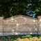 A stone monument set into a shady planter inscribed with the University of Pittsburgh crest