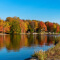 A rippling blue lake reflecting vivid orange and gold autumn trees along its banks beneath a clear blue sky