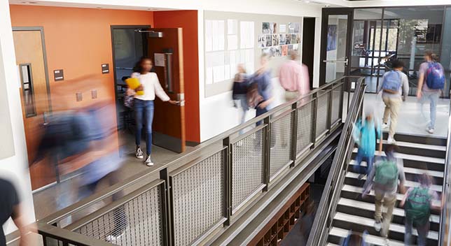 Interior photo of a modern high school with students climbing the stairs and walking through the hallways