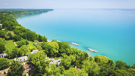 Wisconsin's bright blue lake front adorned with vibrant green trees along the shore.