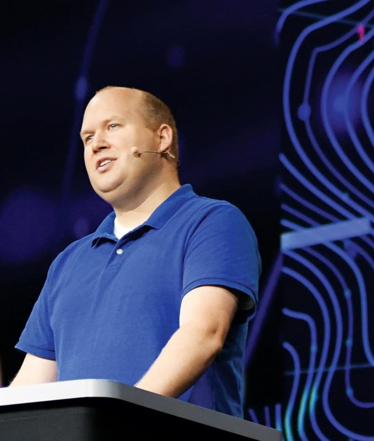 A photo of Kristian Ekenes speaking into a microphone as he gives his onstage presentation
