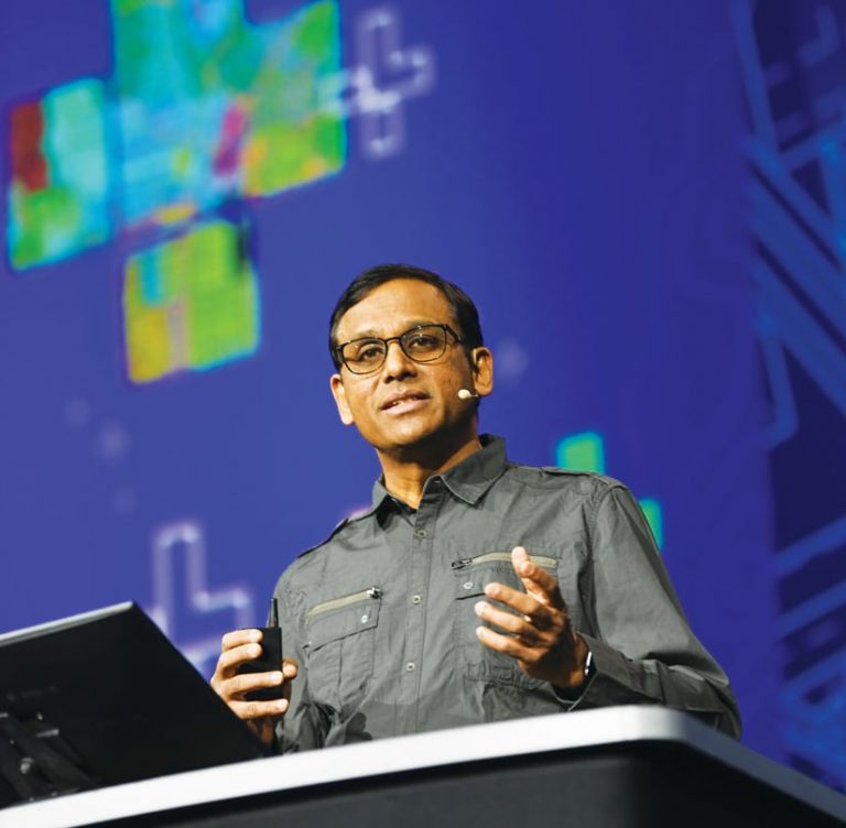 A photo of Jay Theodore speaking into a microphone while he gives a presentation onstage
