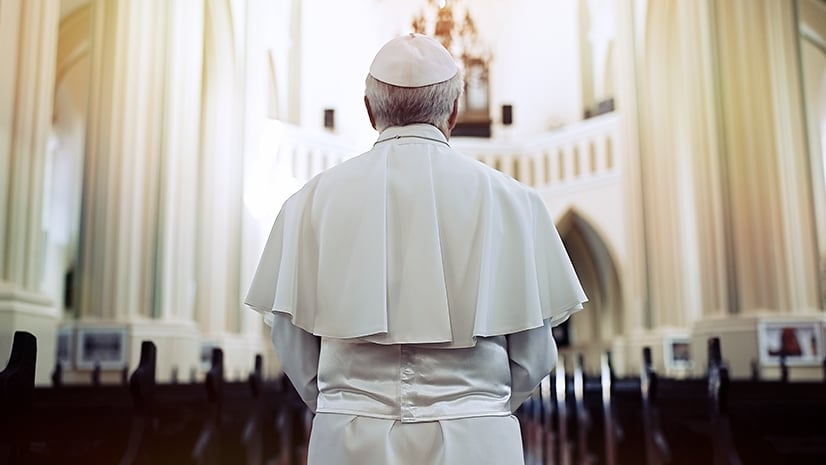 The pope, facing away from the camera, in a church looking towards the altar