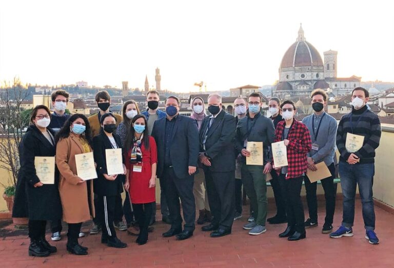 A group of young people with some mentors standing on a balcony overlooking Florence
