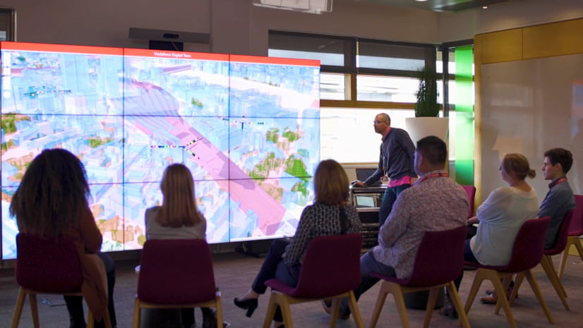 A group gathers around a video wall of Vodafone\'s digital twin to review plans in context