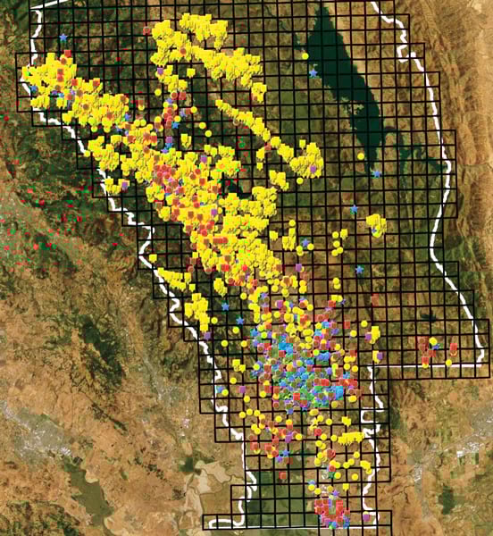 An aerial view is overlaid with hundreds of small circles, squares, and stars of varying colors.