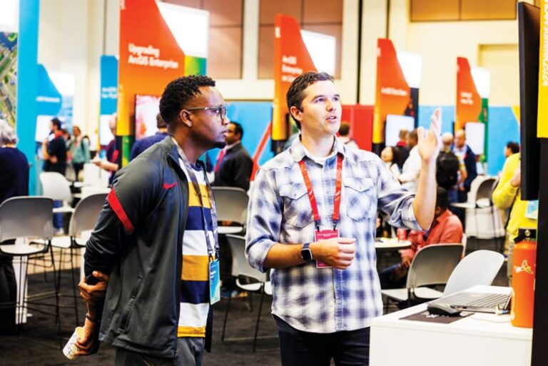 An Esri employee and a DevSummit attendee talk in the expo