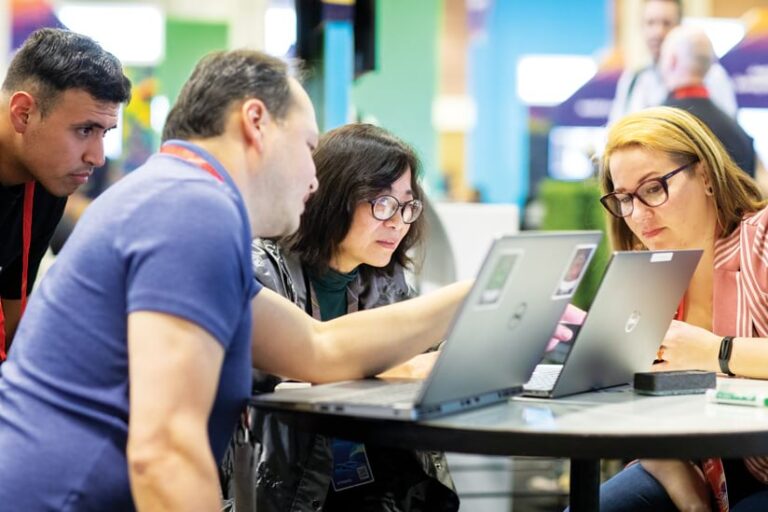 Three people look at a laptop screen.