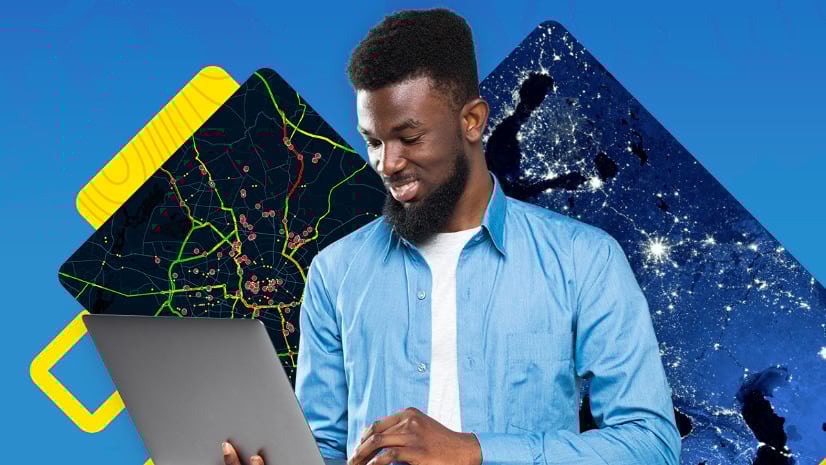 With maps behind him, a person smiles at a laptop.