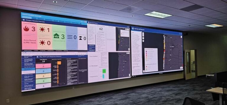Monitors in a room display dashboards and maps with information about an oil spill in Oregon.