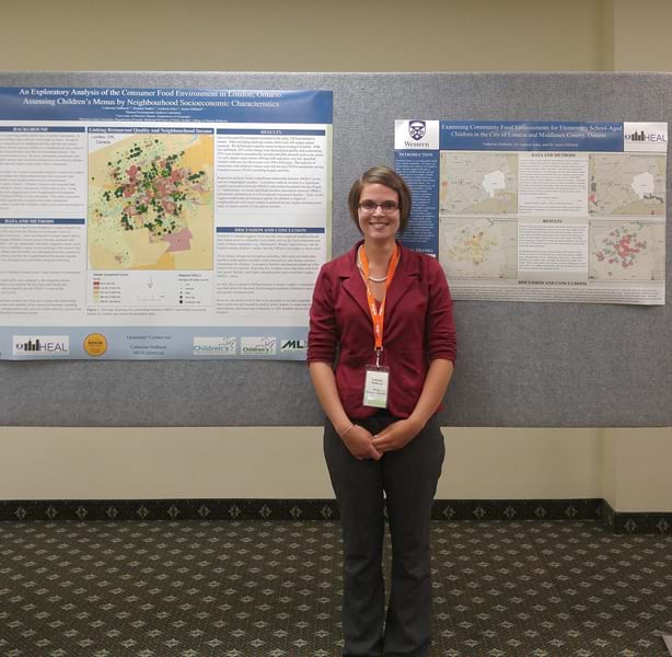 A woman stands in front of a board displaying various geospatial projects she worked on.