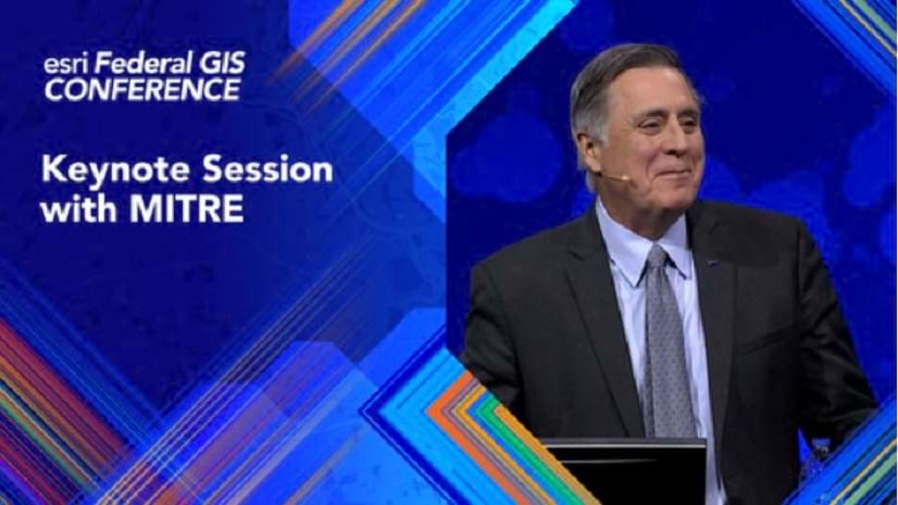 A smiling person wearing a suit and a microphone against a mostly blue design and the title, \'esri Federal GIS CONFERENCE\'