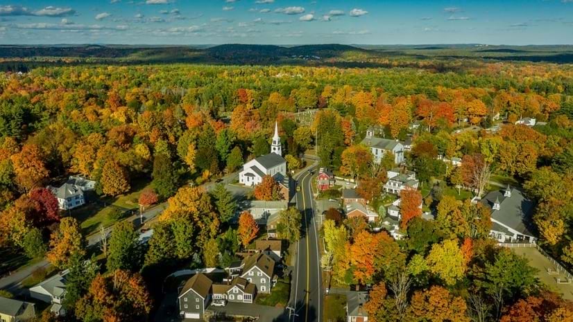 Trees of various fall colors surround a neighborhood of country homes and streets