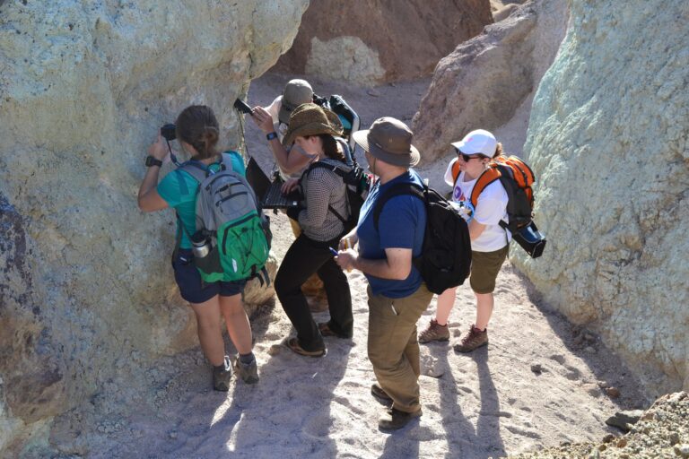 A group of people outdoors examining a large rock