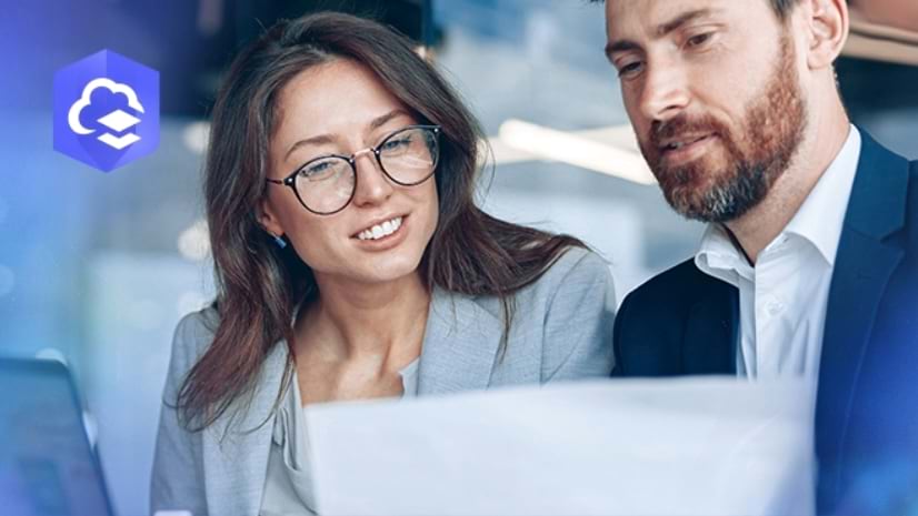 Two young professionals looking at a laptop with an inset purple icon