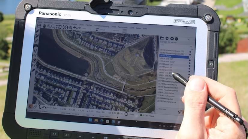 An aerial view of land displayed on a tablet with a hand holding it