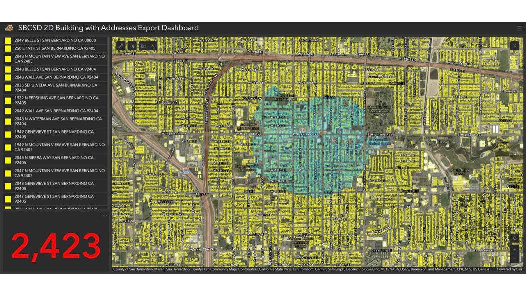 San Bernardino County Sheriff's 2D building export dashboard showing aerial view of densely populated residential neighborhoods with color-coded evacuation zones (yellow and blue areas), street-level detail of individual addresses, and a count of 2,423 total addresses tracked during the Bridge Fire evacuation.