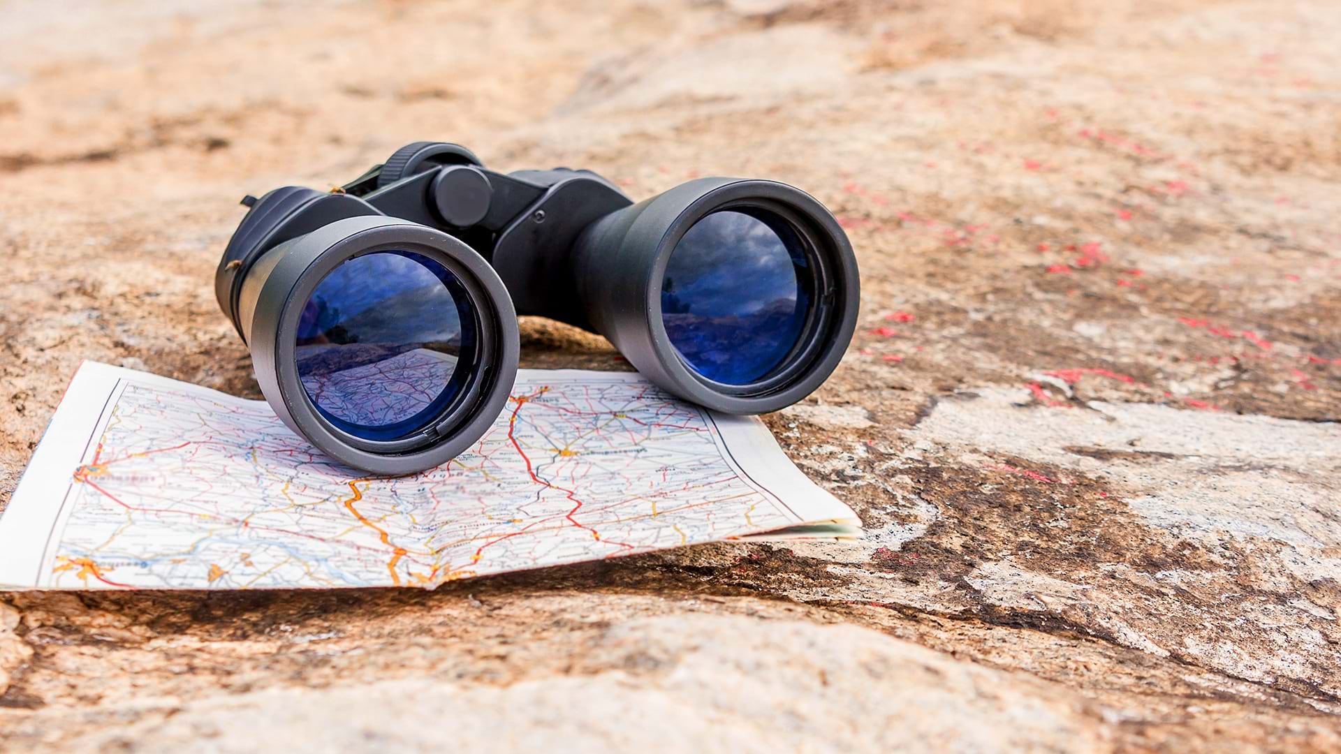 Binoculars resting on a map suggest the challenge of a job seeker