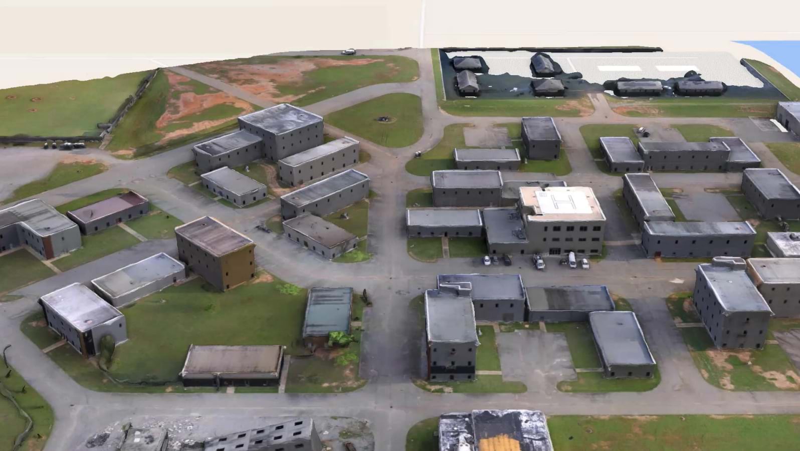 Drone-generated 3D photogrammetric model showing aerial view of Guardian Center training facility with multiple concrete buildings, roads, and training areas rendered in three-dimensional detail from aerial imagery