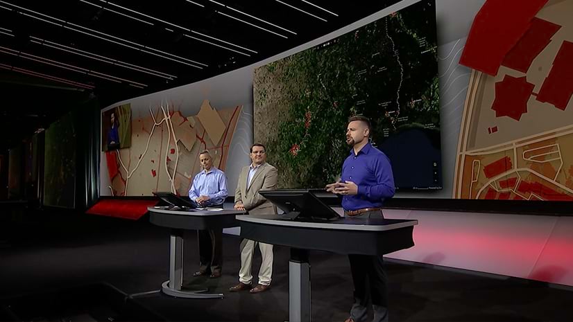 Three people presenting on the Plenary stage at Esri UC
