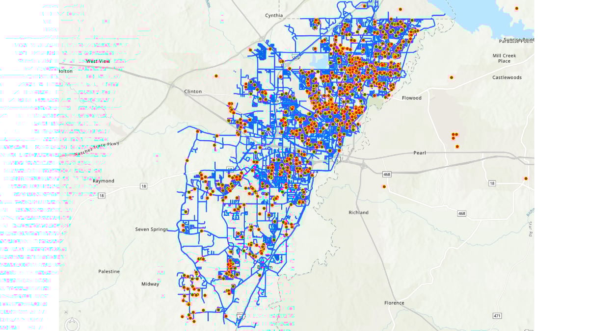 Map of Jackson, Mississippi showing the city's water service area with numerous green dots indicating locations of leak repairs throughout the distribution network. The map includes ward boundaries, major highways in red lines, and the Pearl River running through the eastern portion of the service area. JXN Water and IMS Engineers logos appear in the bottom right corner.