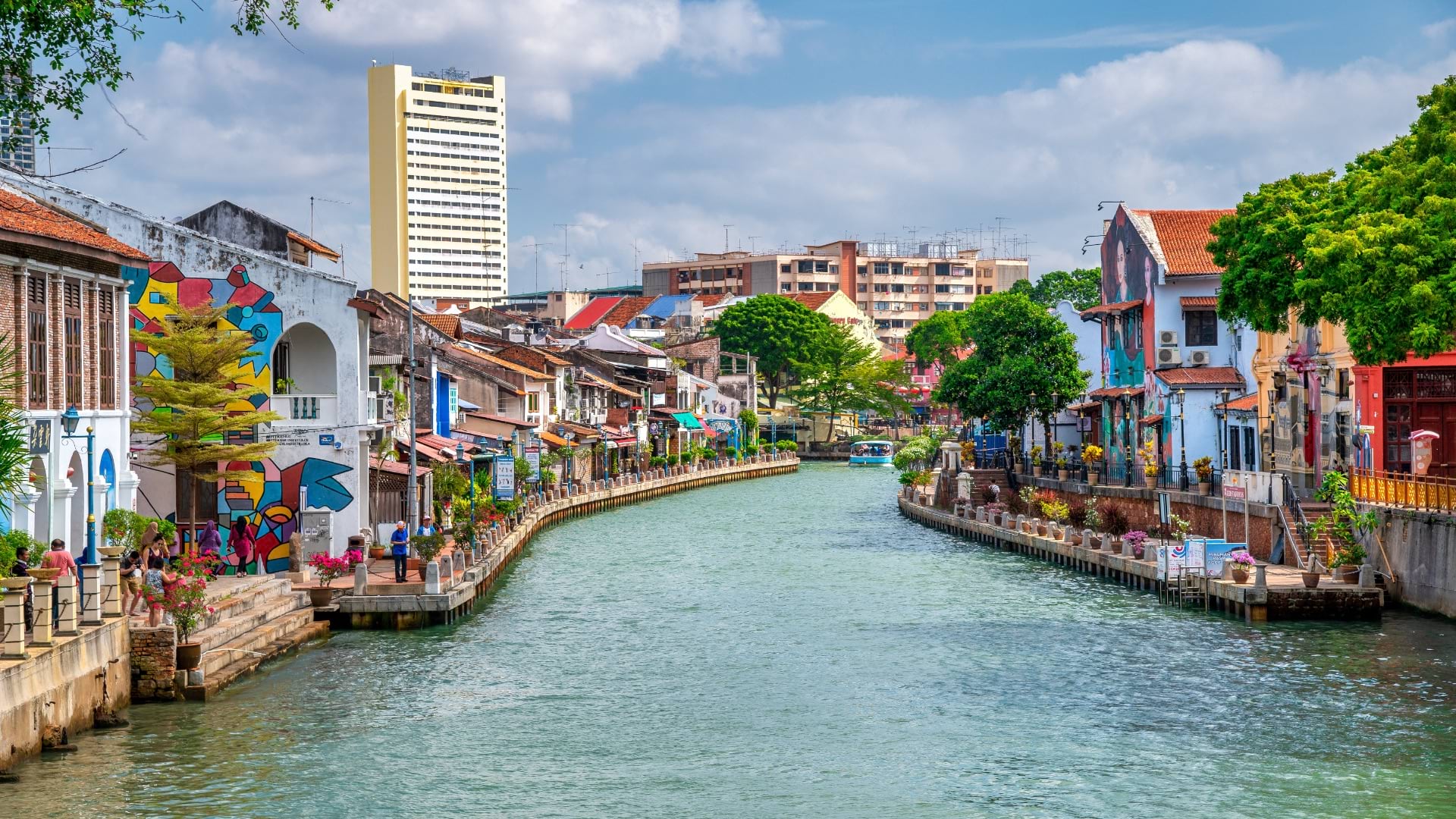 Colorful riverside district in Malacca, Malaysia with historic buildings and modern towers in background