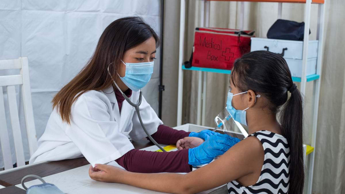 Doctor examining young girl patient wearing masks in clinical setting