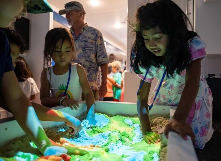 Young students sifting through a multicolored sandbox with their hands
