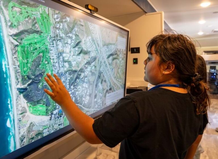 A young girl exploring a map displayed on a touch screen monitor