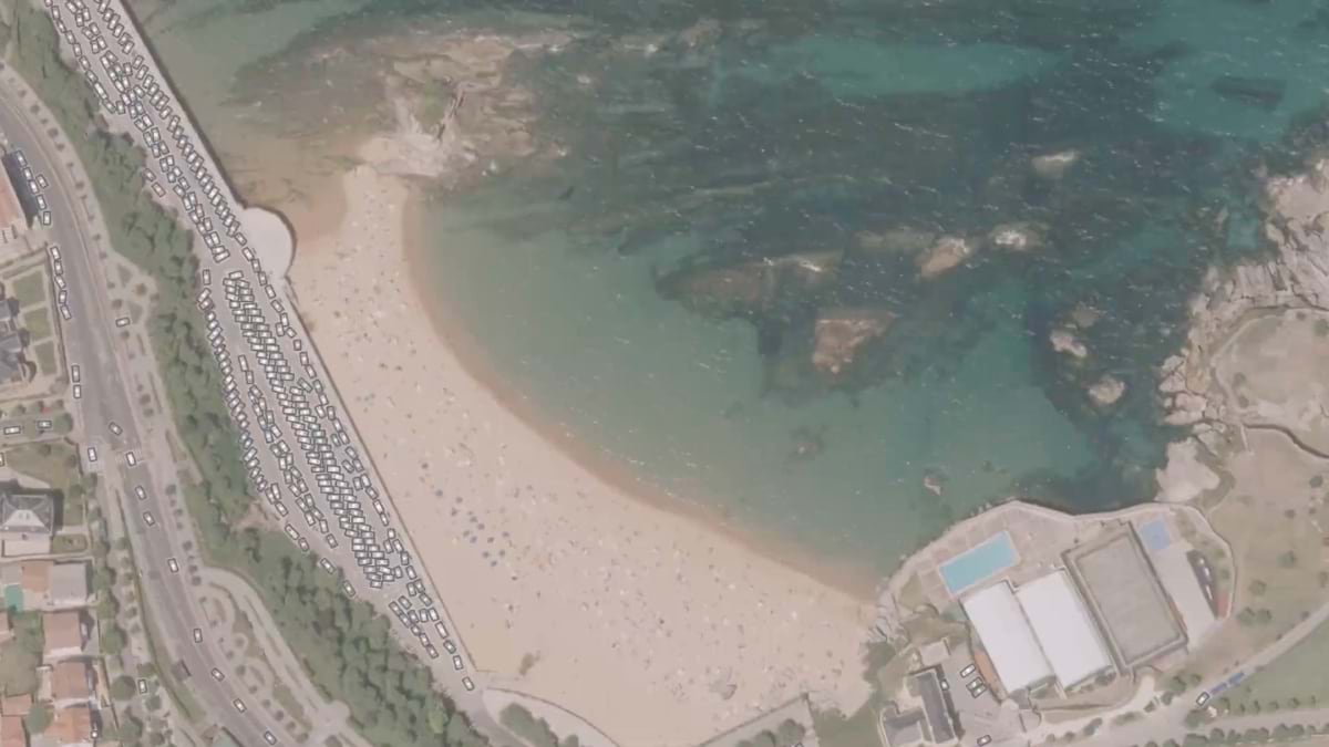 Overhead view of Cantabria beach showing parked vehicles along the shore, sandy beach area, and turquoise coastal waters