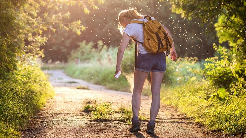 A hiker sprays tick repellent, showing the importance of spotting, analyzing, and adjusting to conditions