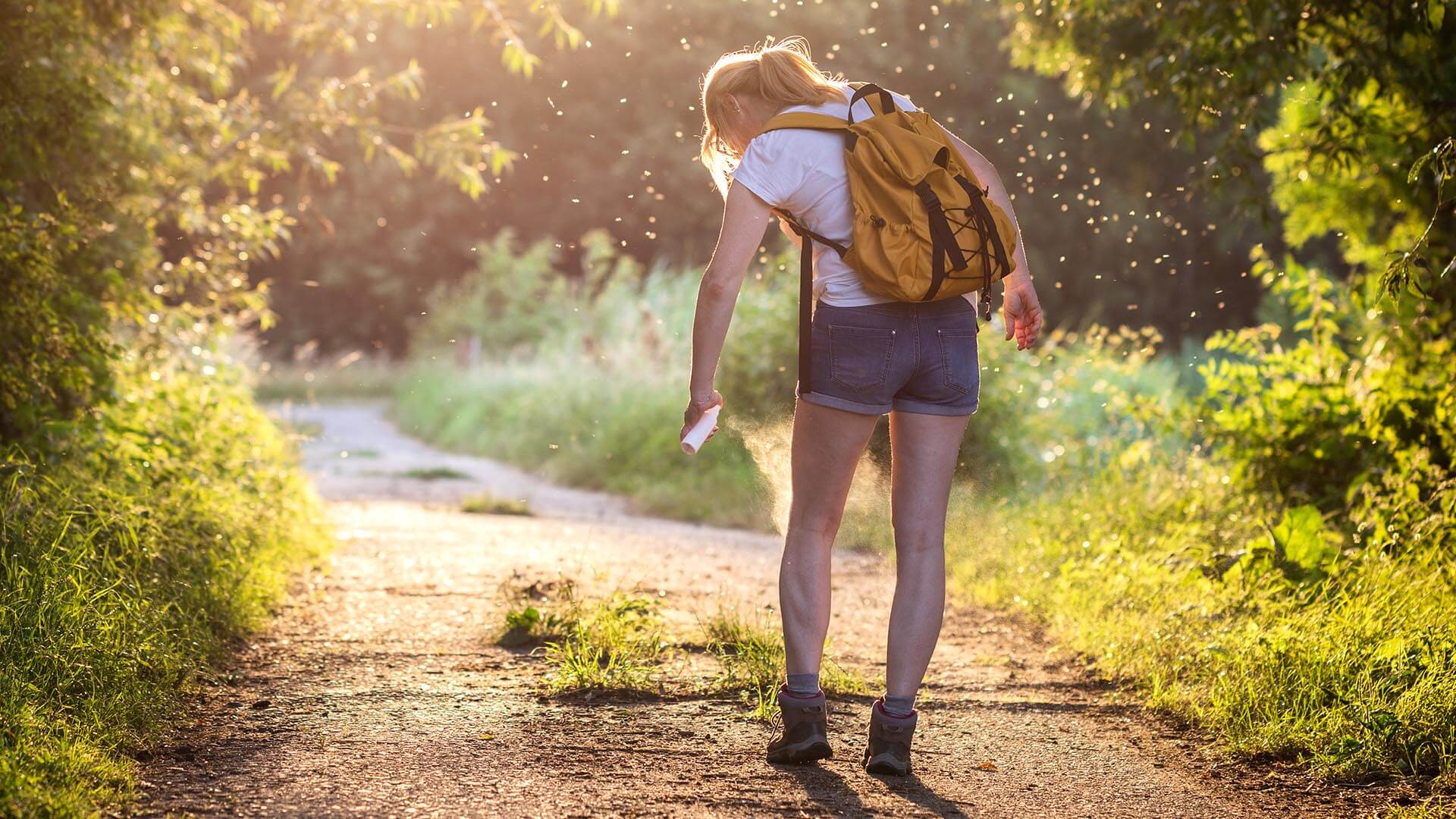 A hiker sprays for ticks, representing the importance of spotting, analyzing, and adjusting to conditions