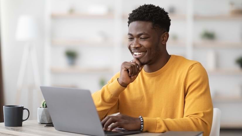 A smiling young man working on a laptop