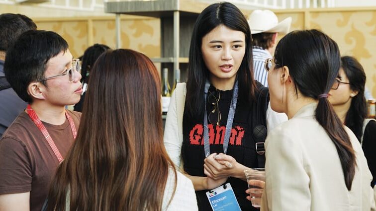 Four young people standing in a circle, talking. They all have conference badges on.