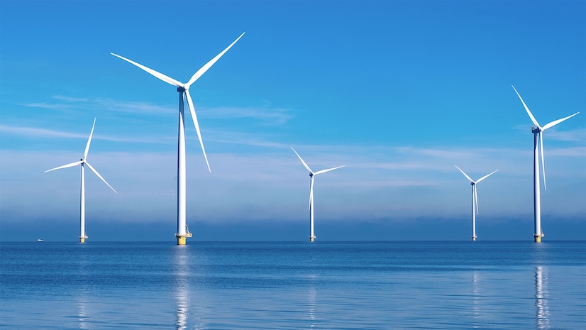 Offshore windmill park with clouds and a blue sky
