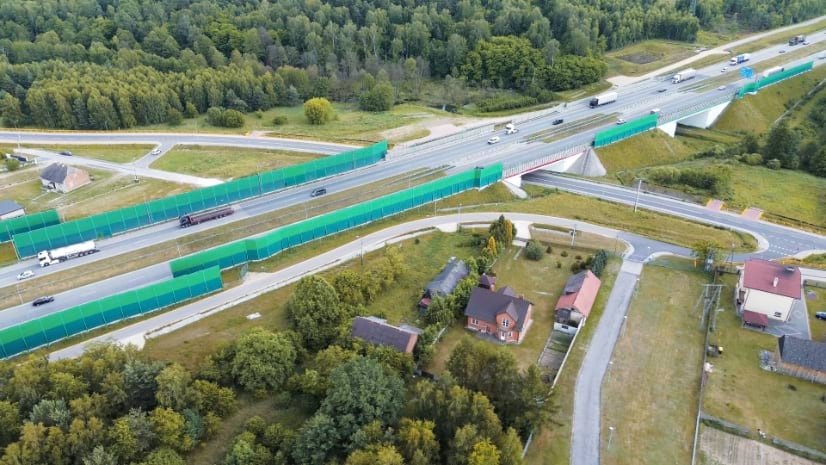 A busy European road with trees and homes on either side