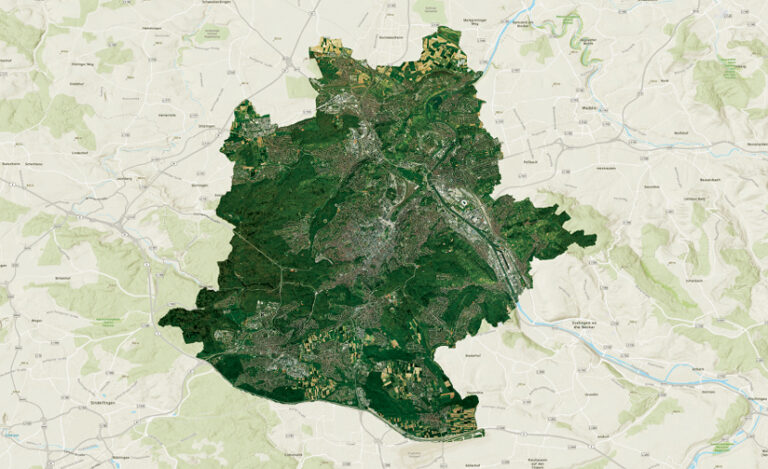 A map showing an administrative area as a detailed satellite image overlaid on a topographic map of the surrounding region. The satellite view displays a mix of urban development, green spaces, and infrastructure.