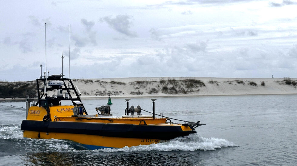 Crewless autonomous survey boat equipped with navigation sensors and sonar systems operating in shallow coastal inlet waters.