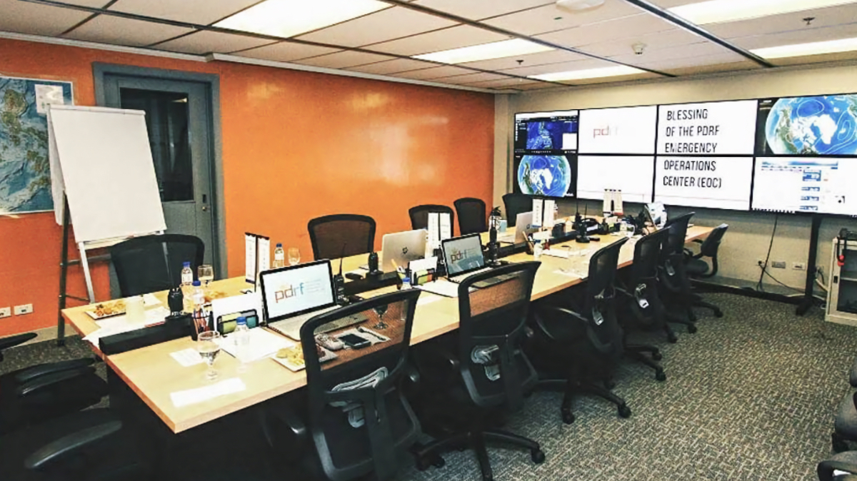 PDRF's first Emergency Operations Center in 2016 showing workstations with computers, wall screens displaying weather data and blessing ceremony sign.