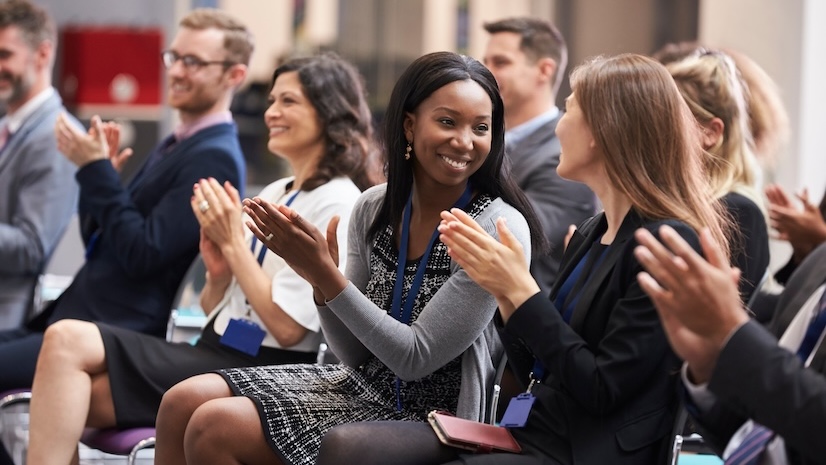 A group of people applauding at a conference