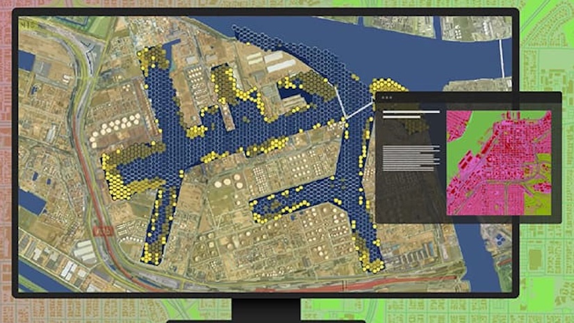 A computer monitor showing an aerial map with an inset image of a pink map