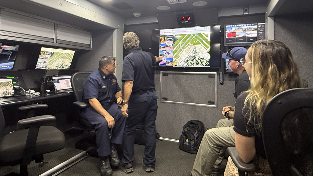 emergency managers inside mobile command unit viewing multiple screens showing live camera feeds of Navy air show grounds.