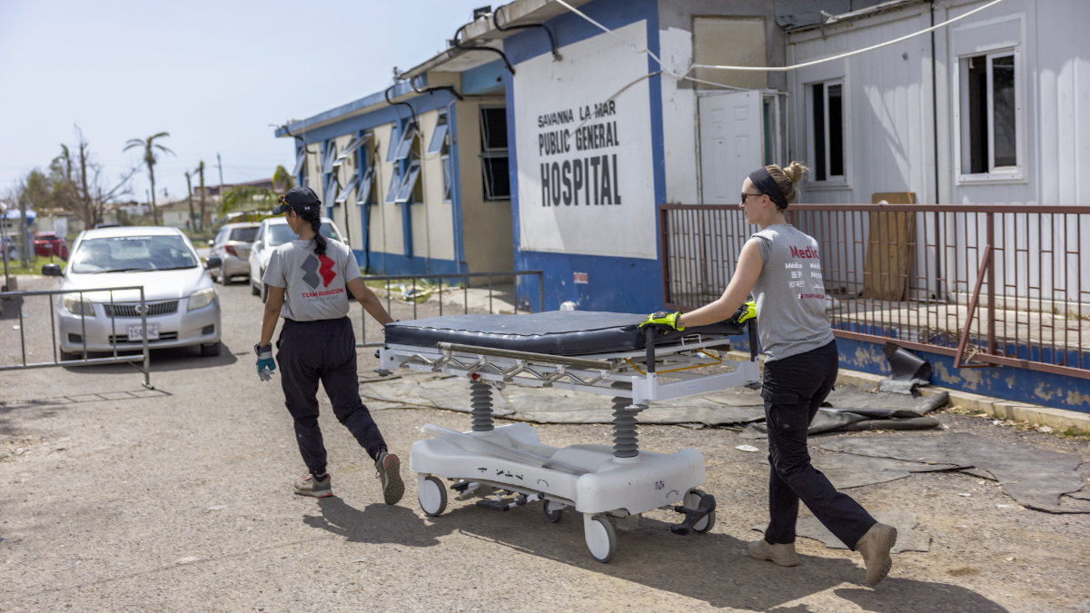 Two Team Rubicon volunteers wheel a gurney outside the storm-damaged Savanna-la-Mar Public General Hospital in Jamaica.