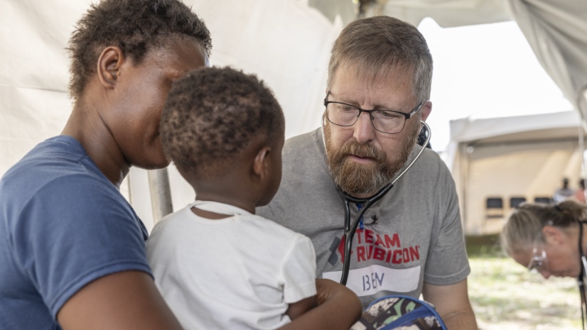 A Team Rubicon medical volunteer examines a young patient at one of two field clinics established near Savanna-la-Mar.