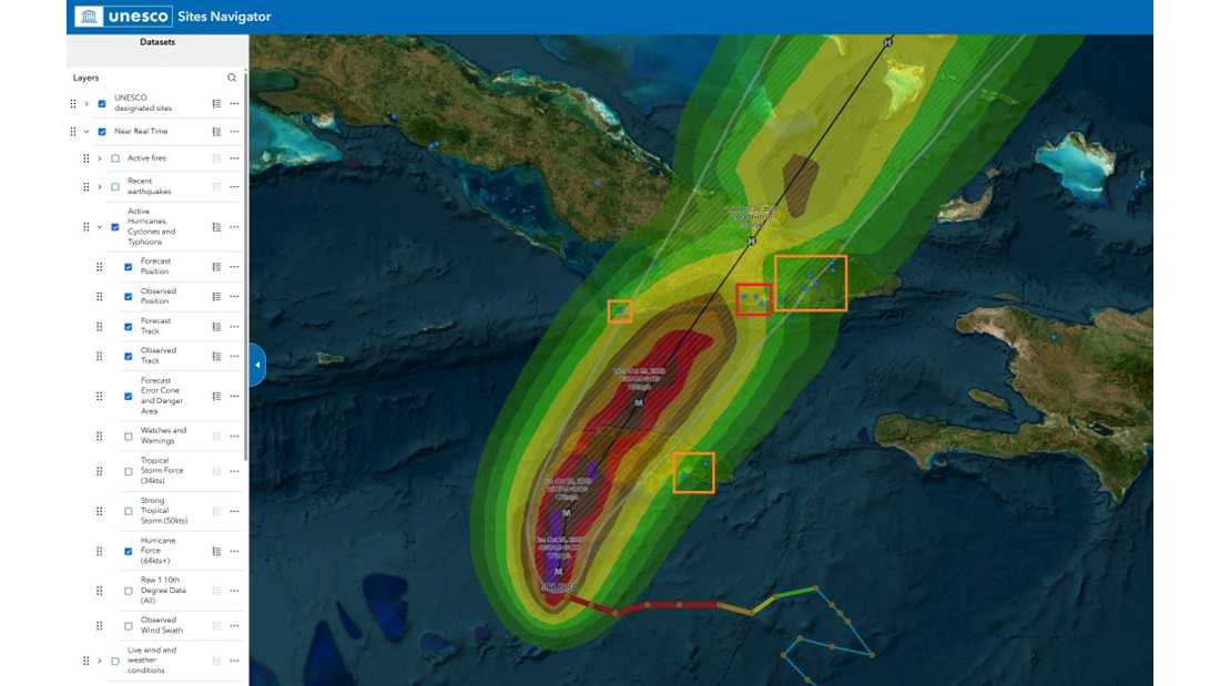 UNESCO Sites Navigator Advanced view showing Hurricane Melissa's forecast track and wind radii over the Caribbean Sea in October 2025. Concentric colored bands — from red at the storm's core to green at its outer edge — show wind strength zones. The storm track runs northeast. Orange highlighted boxes mark UNESCO-designated sites potentially in the storm's path. The left panel shows active layer controls including forecast track, observed track, watches and warnings, and hurricane force winds.