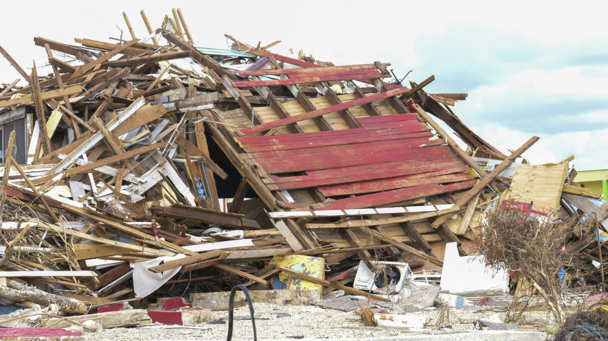 A massive pile of splintered lumber and building debris on a Jamaican beach following Hurricane Melissa's storm surge.