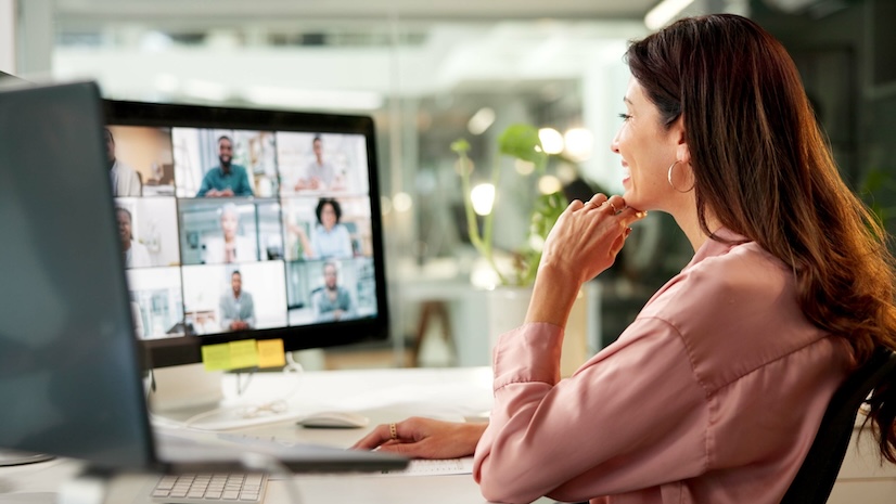 A smiling woman at her desk joining a virtual meeting